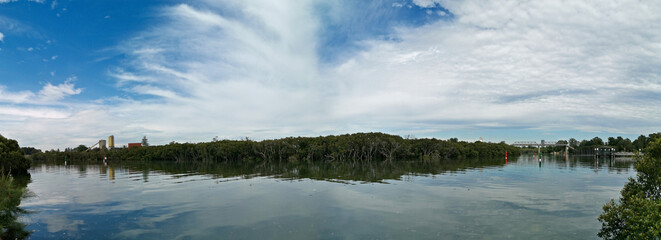 Fototapeta premium Beautiful panoramic view of a river with reflections of trees, deep blue sky and light clouds on water, Parramatta river, Rydalmere, Sydney, New South Wales, Australia 