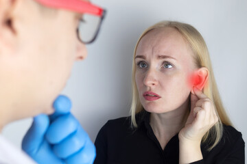 A woman suffers from pain in the ear. The auditory meatus hurts due to otitis media, cerumen plug,...