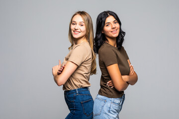 Two young women standing back to back againt the white background.
