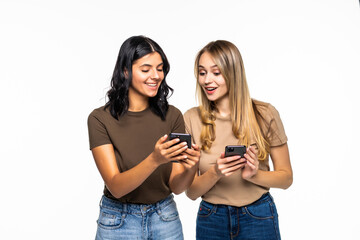Two cheerful pretty young women using on cell phones and laughing on white background
