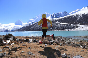 Fototapeta premium Woman trail runner cross country running in winter mountains