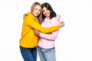 Obraz premium I missed you so much. Two pretty girlfriends women holding each other in close hugs wearing casual bright hoodies jeans isolated white background