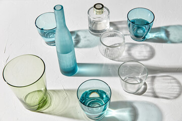 glassware concept - different glasses and bottles dropping shadows on white surface