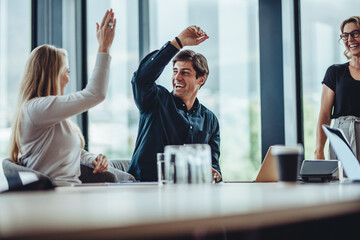 Business colleagues giving a high five in meeting room