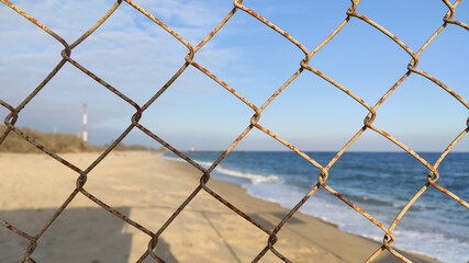 View of the sea through the fence mesh. Close-up focus railing mesh