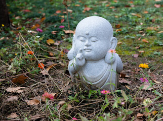 A small statue of a little monk meditating at a garden in historic Buddhist Jinshan Temple, Zhenjiang, Jiangsu, China.