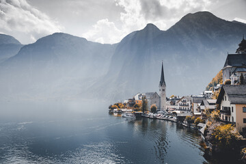 Hallstatt surrounded by a lake and mountains under a cloudy sky and bright sunlight in Austria