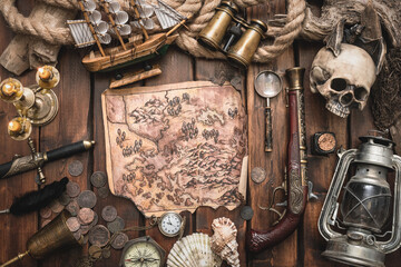 Pirate treasure map and other accessories on the brown wooden table concept background.