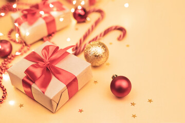 Christmas and New Year blurred backdrop with copy space. Festively decorated  Gift boxes,  cane lollypops, christmas balls on golden background.