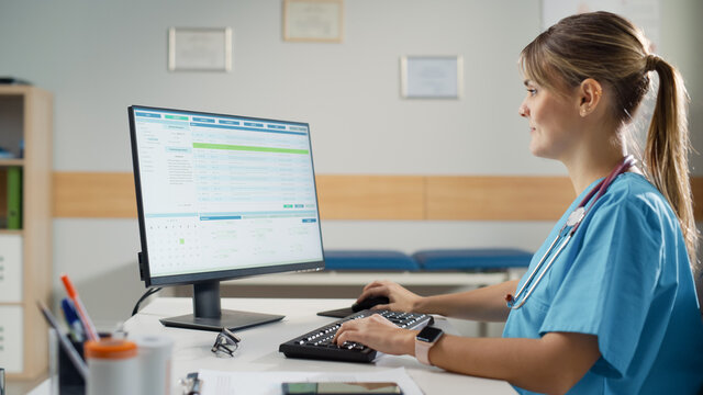 Hispanic Doctor's Office: Experienced Head Nurse Sitting at Her Desk Working on Personal Computer in Data Software. Medical Health Care Specialist Filling Prescription Forms, Checking Analysis Results
