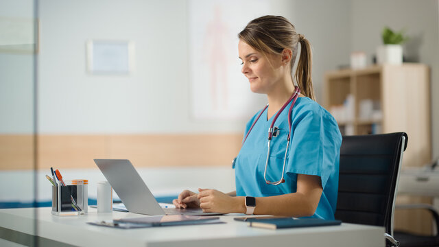 Doctor's Office: Experienced Head Nurse Sitting At Her Desk Working On Laptop Computer. Medical Health Care Specialist Checking Test Results, Emailing Patients And Prescribing Medicine.