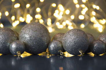 Christmas decorations on dark background. Gold colored glittery baubles, warm lights and cheerful mood. Selective focus on the tree balls, blurred background.