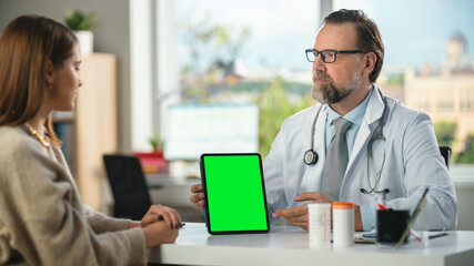 Naklejka na ściany i meble In a Doctor's Consultation Room: Professional Physician Uses Green Chroma Key Digital Tablet Computer to Explain Test Results to a Female Patient and Prescribes Medicine.