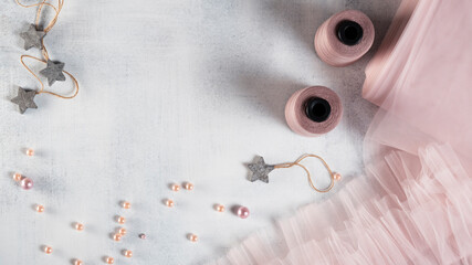 Tailor workplace with pink tulle, beads and spool of threads. Selective focus.