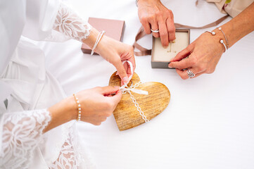 Beautiful blonde woman in white dress on her wedding day before getting married, her mother shares jewelry.