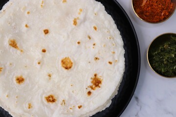 Rice bhakri, Chawal ki roti. It is a round soft flatbread. Usually eaten with fish, chicken or mutton thali. Served with garlic & green chutney. Copy space.