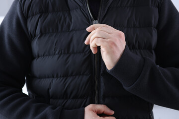 Man zips up a black jacket. Fashionable and stylish youth clothing concept
