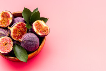 Fresh figs in a bowl with green leaves. Top view