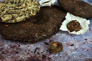 Pressed round pancakes and bricks of puer tea of different kinds. Dry Chinese puer tea of high quality.