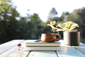 Wooden brown cup and notebooks and  black plant pot 
