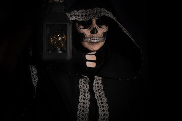 The death. Artistic makeup representing death with an old lantern, Low Key image, selective focus.