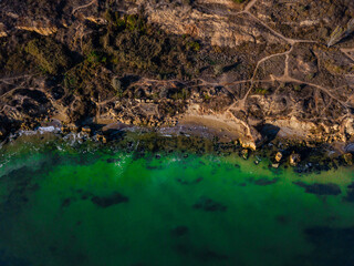 Aerial view of green sea waves crashing on the rocks