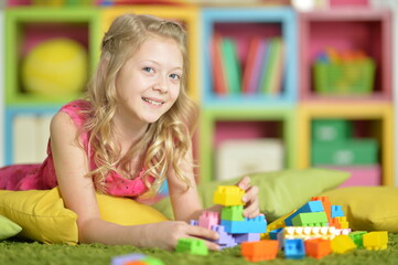 Little girl playing with colorful plastic blocks