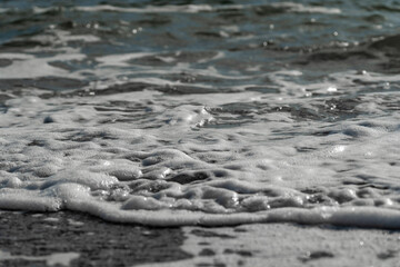 Close up of small wave spreading on the beach became a sea foam
