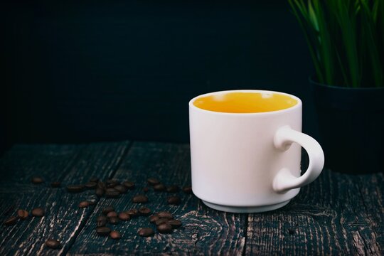 White mug and coffee zerg on an old textured wood table with a houseplant.