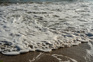 Close up of sea foam on the sandy sea beach