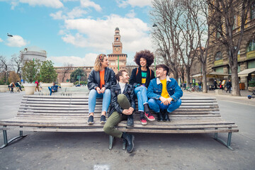Group of four multiethnic best friends outdoor sitting bench