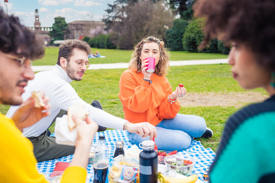 Four young students multi ethnic friends outdoor doing pic nic