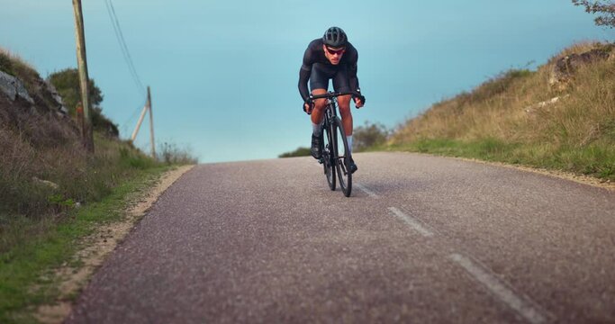 Professional cyclist struggling to ride bicycle uphill