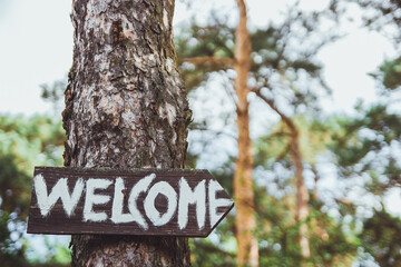 welcome sing on the tree. white letters on the wooden board. Inviting board to the wedding party.