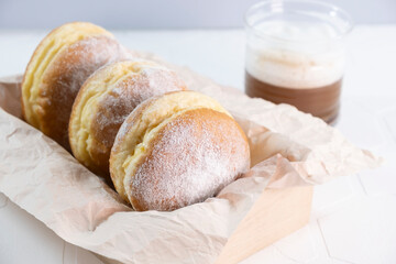 glass cup of coffee and doughnuts on wooden white background
