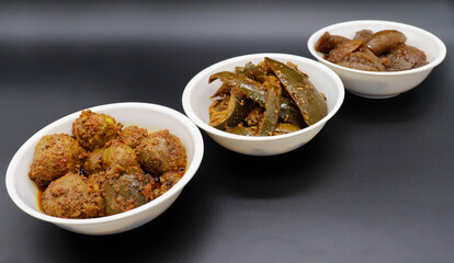 Group photograph of indian pickles or achar like amla pickle, mango pickle and lemon pickle, sarved in white ceramic bowl, side angle shot