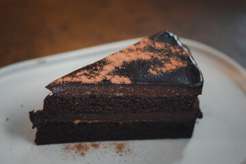 Close up triangle slice piece of delicious dark chocolate fudge cake