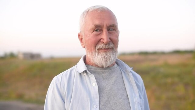 Old man with gray hair and beard on the countryside