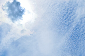 close-up - the sun covers a large cloud against a blue sky and an unusual cloud shape