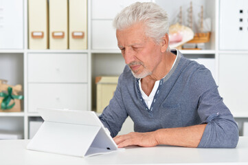 Fototapeta premium Portrait of thoughtful senior man with tablet