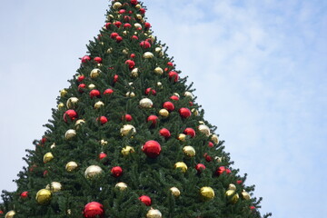 christmas tree with garlands of glowing and decorations, blue sky