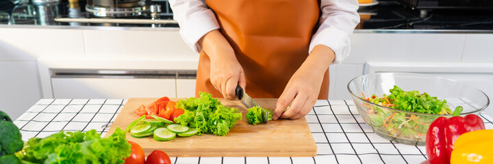 young Asian woman is preparing healthy food vegetable salad by Cutting ingredients on cutting board on light kitchen, Cooking At Home and healthy food concept