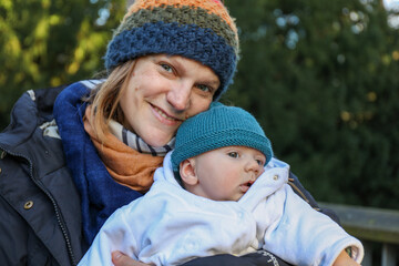 Portrait of a smiling mother with a baby boy son in the park in the winter 