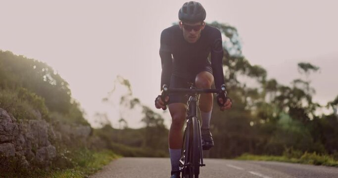 Professional cyclist training bicycle ride up hillside at sunrise
