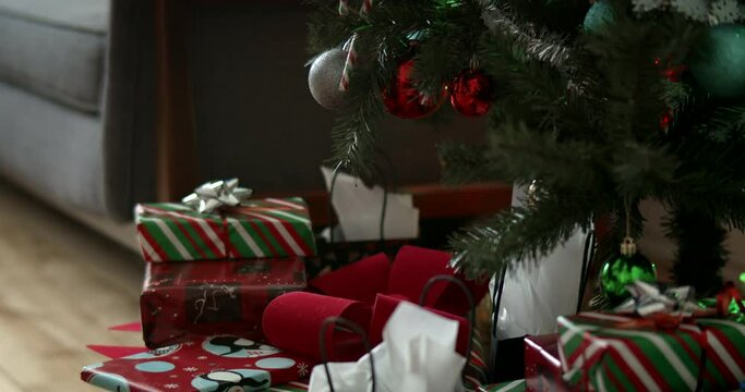 Closeup of Christmas tree gifts and decorations. Person placing presents onto large pile the night before xmas. 
