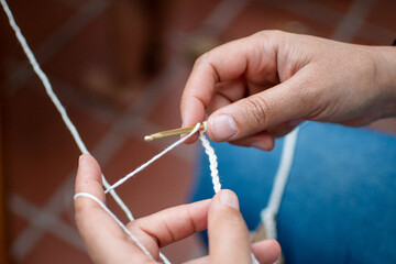woman's hands knitting with wool and crochet needles