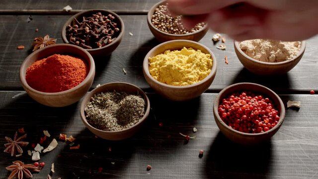 Chef taking dry herbs by hand. Spices and herbs on a table.