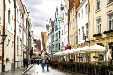 Fototapeta na wymiar Watercolor drawing of Medieval streets of Old Town of Tallinn with beautiful colourful buildings and walking people, Estonia