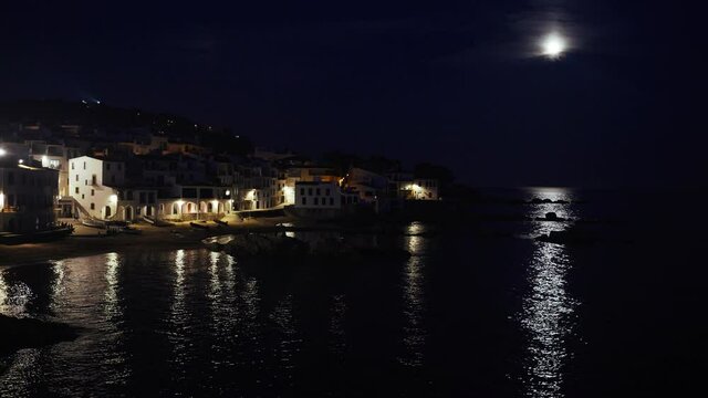 Beautiful Mediterranean village at evening. Night views on a small town on a sea coast. Water and lights of Calella de Palafrugell in Spain. Costa Brava vacation an chill. White houses on the beach..