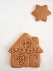 Gingerbread cookies in the shape of a house and stars on a white background